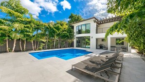 A modern two-story house with a swimming pool and outdoor seating area.