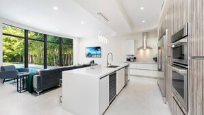 A modern kitchen with a central island, built-in appliances, and large windows overlooking a pool.