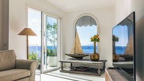 Een woonkamer met een bank, een tafel met een model zeilboot, een vaas met bloemen en een televisie.