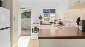 A modern kitchen with white cabinets, a wooden countertop, a stove, and a sink. - Beach Getaway Villa: 2BR Fun! (Bicton)