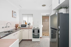 A kitchen with a sink, microwave, stove, and refrigerator.
