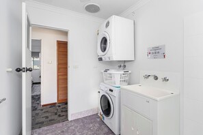 Une buanderie équipée d’un lave-linge, d’un sèche-linge et d’un évier.