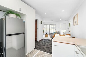 A modern kitchen with a built-in LG refrigerator, a dining area with a round table and chairs, and a view into the living room.
