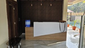 A reception area with a wooden reception desk, a water dispenser, and a ceiling fan. - Shrikar Resort (Nagaon)