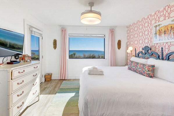 A bedroom with a large bed, a dresser, a television, and a view of the ocean. - Gulf Front, 2 BR/ 2 BA Private Beach Access Pool & Bikes (Seagrove Beach)