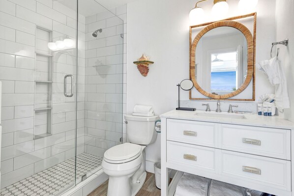 A modern bathroom with a glass-enclosed shower, a white toilet, and a vanity with a large mirror. - Gulf Front, 2 BR/ 2 BA Private Beach Access Pool & Bikes (Seagrove Beach)