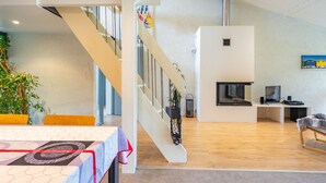 A spacious living area with a staircase, a fireplace, and a dining table. - Spacious Villa 10 min from Royan – 4 Bedrooms, Garden, Terrace, Ideal for Families and Friends (Saujon)