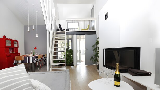 A modern living room with a sofa, a TV, a dining area with chairs, and a staircase. - Spacious Villa 10 min from Royan – 4 Bedrooms, Garden, Terrace, Ideal for Families and Friends (Saujon)
