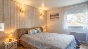 A bedroom with a bed, two wall-mounted lamps, a window with curtains, and a picture on the wall. - Spacious Villa 10 min from Royan – 4 Bedrooms, Garden, Terrace, Ideal for Families and Friends (Saujon)