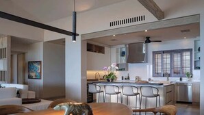 Een moderne keuken met een centraal eiland, barstoelen en een eethoek met een houten tafel en stoelen.