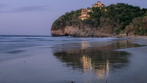 A beachfront property with a cliffside view, featuring multiple levels of buildings and lush greenery.