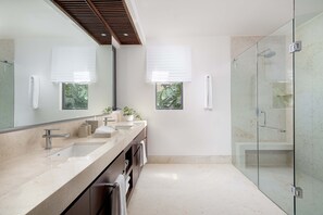 A modern bathroom with a large mirror, two sinks, a glass shower enclosure, and a potted plant on the vanity. - Casa Ravello: Luxury Villa, Full Service & Premier Golf (Punta Mita)