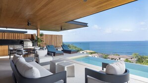 A modern outdoor living area with a pool, lounge chairs, and a view of the ocean. - Casa Ravello: Luxury Villa, Full Service & Premier Golf (Punta Mita)