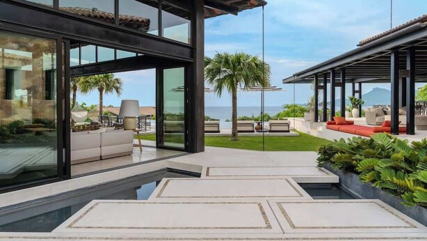 Un'area relax esterna moderna con piscina, posti a sedere e vista sull'oceano.