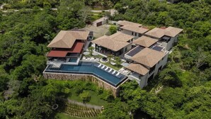 Una moderna località turistica con diverse ville, una piscina e rigogliosa vegetazione tutt'intorno.