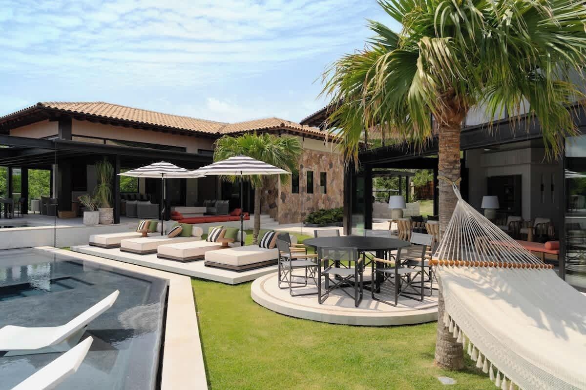 A modern outdoor living area with a pool, seating, and a hammock.