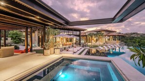 A luxurious outdoor pool area with a clear view of the pool, lounge seating, and a covered patio.