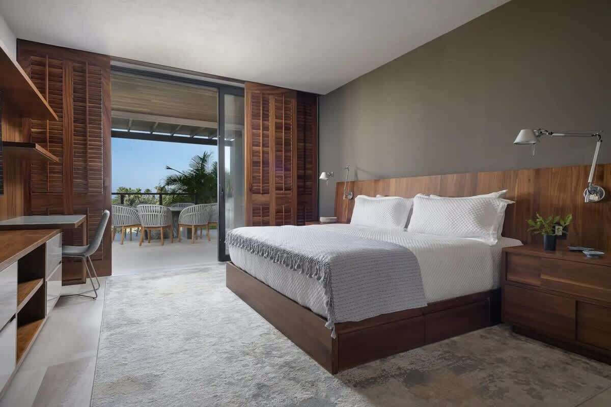 A modern bedroom with a large bed, wooden headboard, and a desk area.