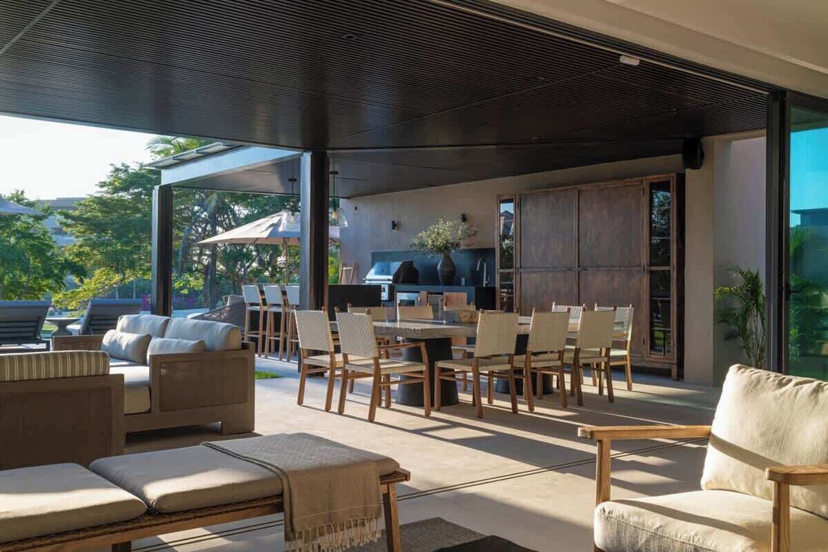 An outdoor living area with a dining table, chairs, sofas, and a grill.