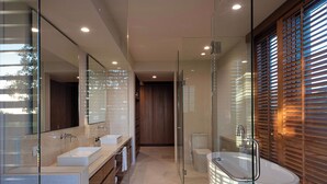 Un baño moderno con cabina de ducha de vidrio, un espejo grande y una bañera.