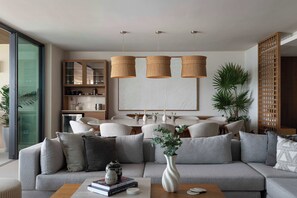 Una sala de estar moderna con un sofá seccional, una mesa de centro y una zona de comedor con una pizarra.