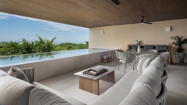 Un espacio exterior moderno con piscina, zona de estar y vista al océano.
