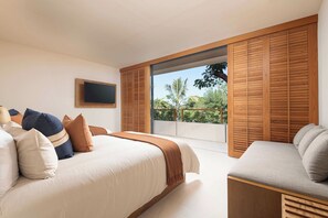 A bedroom with a bed, a sofa, a TV, and a sliding door to a balcony. - Las Olas: 5BR Modern Condo, Private Pool & Surf Club (Punta Mita)