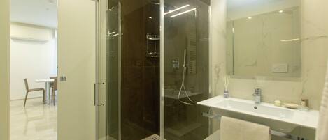 A modern bathroom with a glass-enclosed shower, a white sink, and a large mirror.