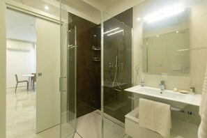 A modern bathroom with a glass-enclosed shower, a white sink, and a large mirror. - Residence Flow-r (Riccione)