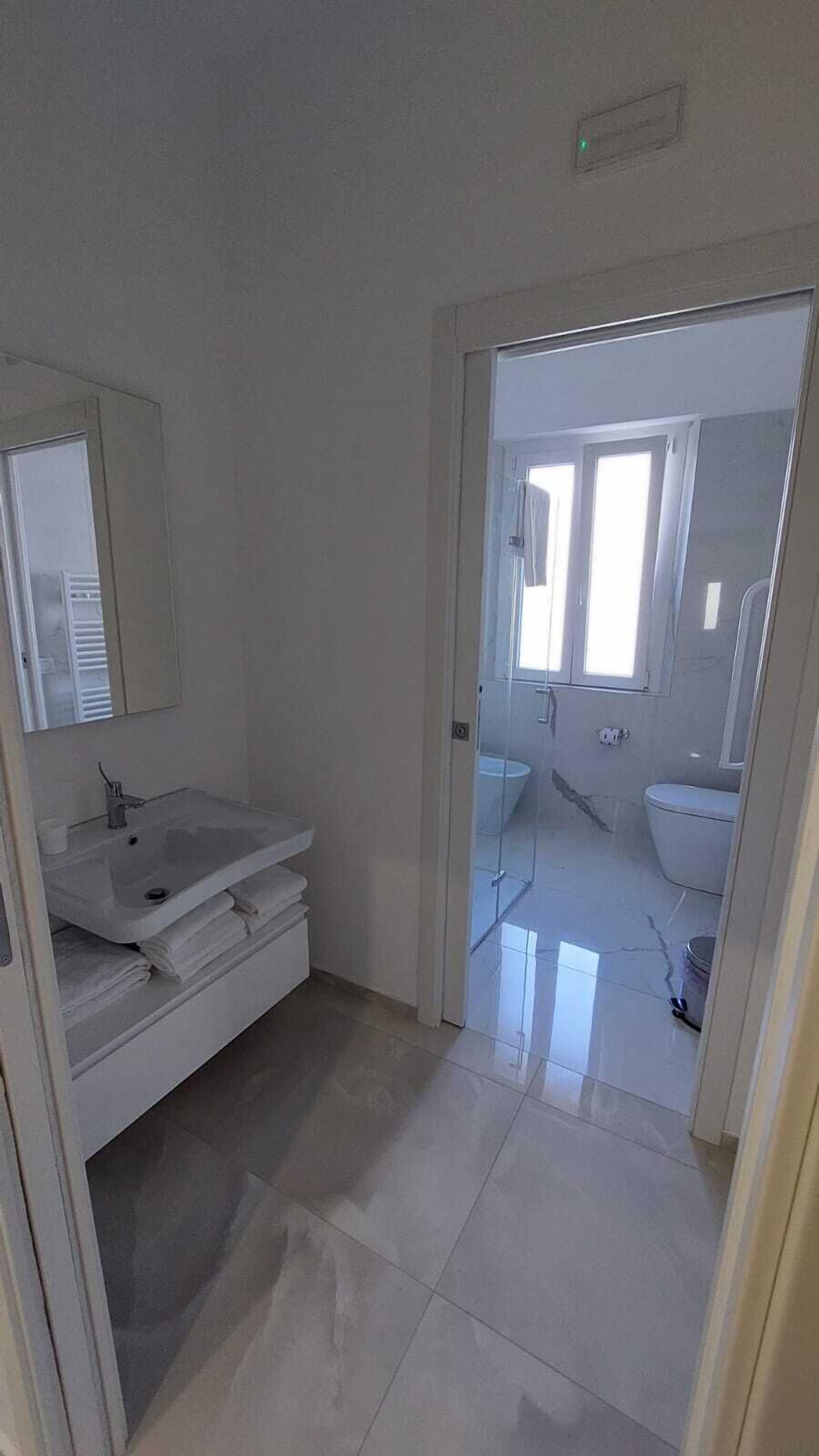 A bathroom with a white sink, mirror, and toilet.