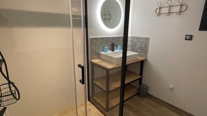 A modern bathroom with a glass-enclosed shower, a round mirror with a light, a wooden vanity, and a wall-mounted towel rack. - Charming chalet in Gérardmer To relax with family and friends  (Gérardmer)