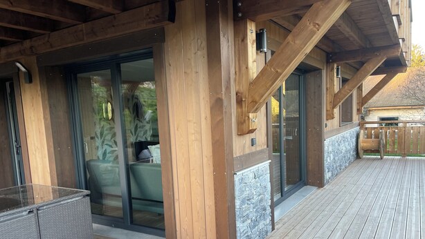 A wooden deck with a glass door leading to a patio area. - Charming chalet in Gérardmer To relax with family and friends  (Gérardmer)