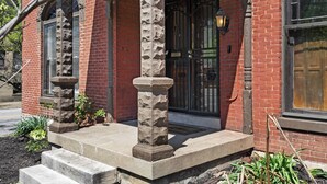 Un edificio de ladrillo con una columna de piedra y escalones que conducen a una puerta con una verja negra.