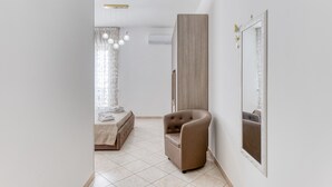 A modern bedroom with a bed, a chair, a large mirror, and a hanging light fixture. - Apartment 'Mirea' with Private Terrace, Wi-Fi and Air Conditioning (Melissano)
