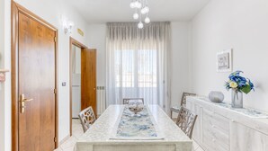 A dining area with a table, chairs, a chandelier, a window with curtains, and a cabinet with a vase. - Apartment 'Mirea' with Private Terrace, Wi-Fi and Air Conditioning (Melissano)