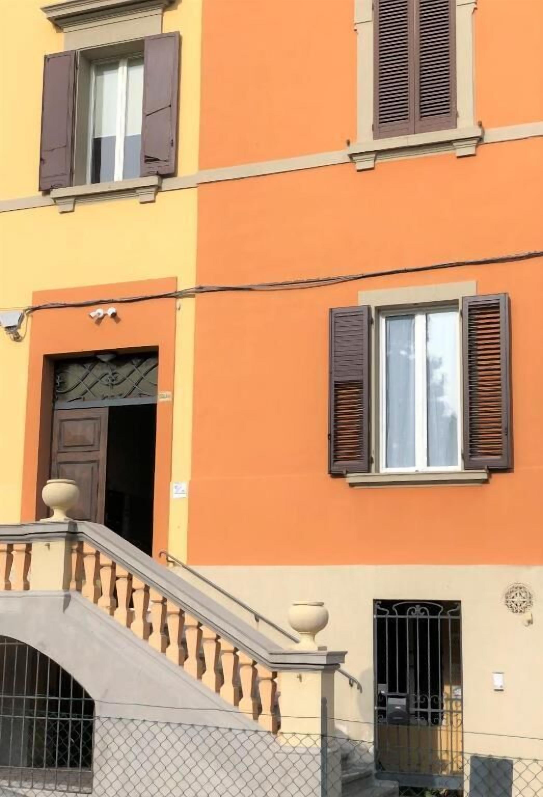 A multi-story building with orange and beige walls, a metal staircase with balusters, and a gated entrance.