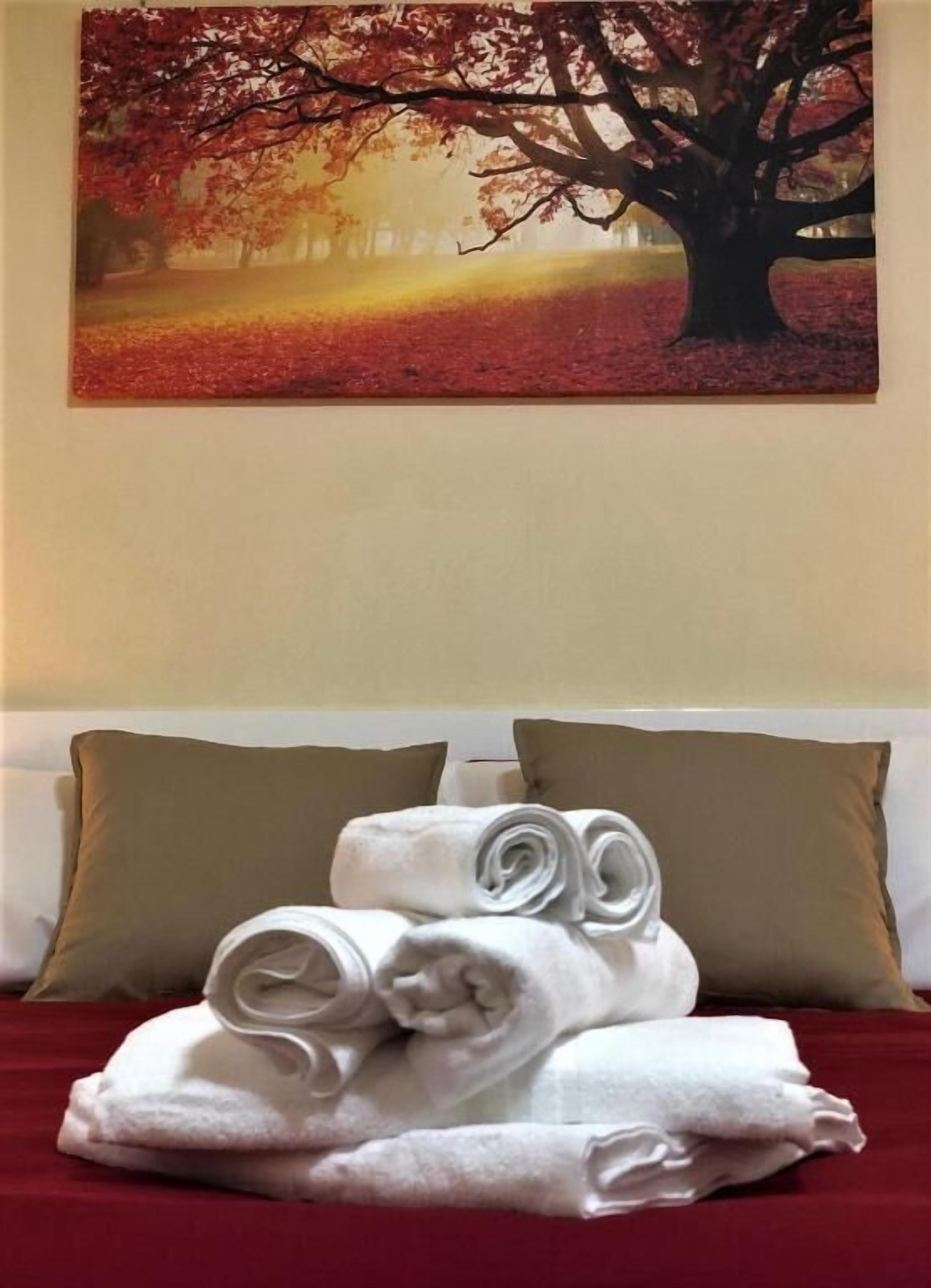 A hotel room with a bed, two pillows, and neatly folded towels.