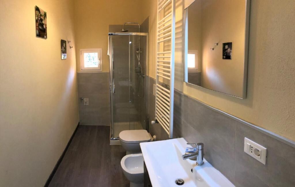 A compact bathroom with a glass-enclosed shower, a toilet, and a sink.
