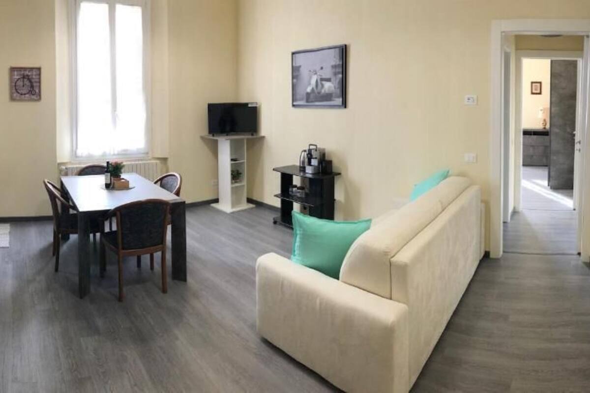 A compact living space with a dining area, a sofa, a television, and a hallway leading to another room.