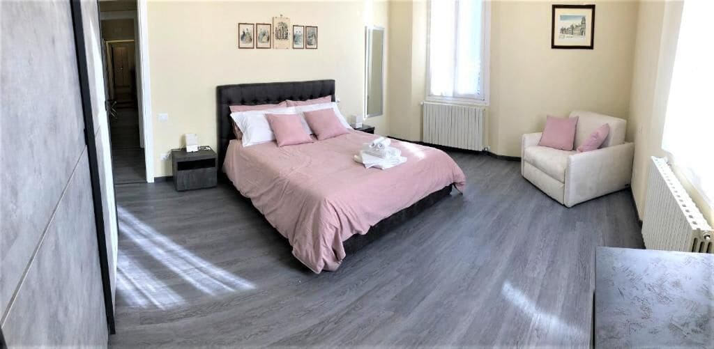 A bedroom with a bed, bedside tables, a chair, and a radiator.