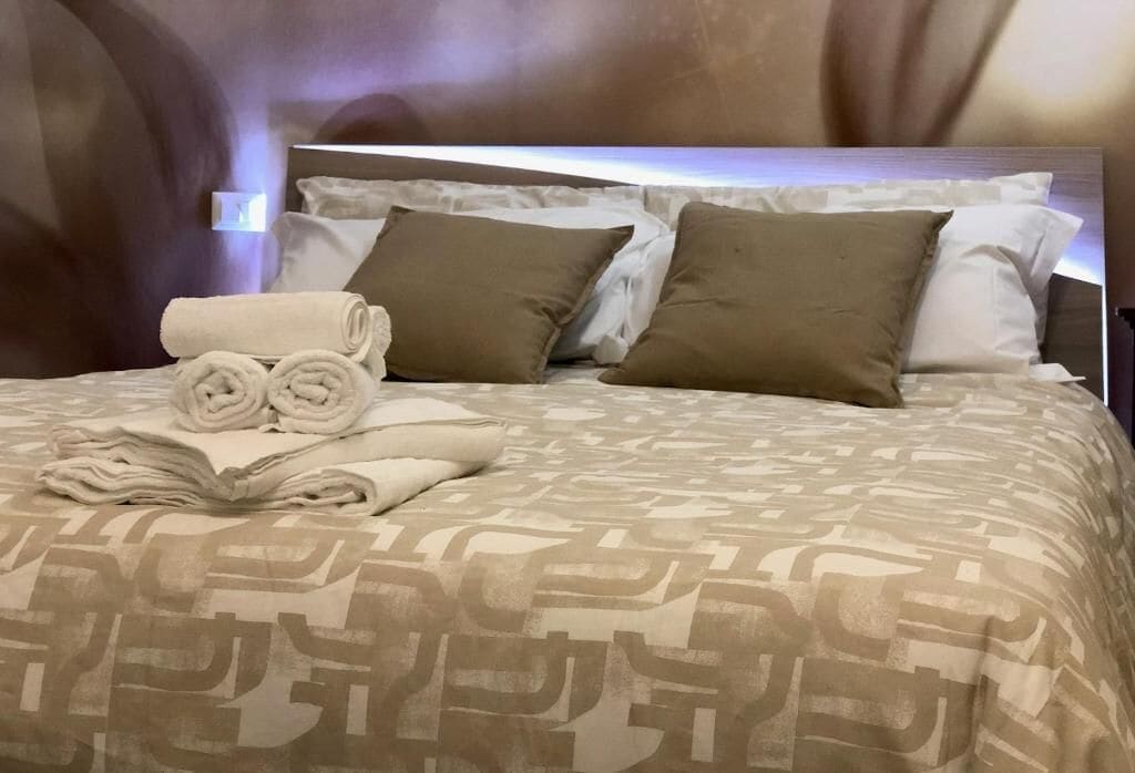 Un lit bien fait, avec des serviettes pliées, deux oreillers et une couvre-lit à motifs.