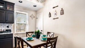 A dining area with a wooden table and chairs, a potted plant, and teal bowls. - Cozy 3BR dog-friendly home just 13 min from Fort Campbell. Sleeps 6 with fast WiFi, a full kitchen, smart TVs and convenient access to APSU/F&M Bank Arena. (Clarksville)
