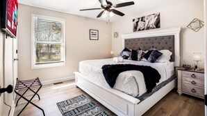 A bedroom with a bed, a ceiling fan, a nightstand, a TV, and a window with blinds. - Cozy 3BR dog-friendly home just 13 min from Fort Campbell. Sleeps 6 with fast WiFi, a full kitchen, smart TVs and convenient access to APSU/F&M Bank Arena. (Clarksville)