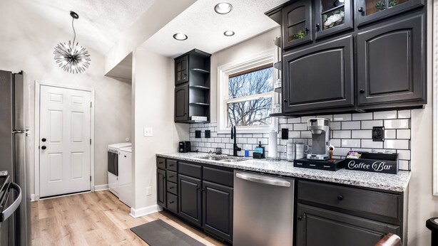 A modern kitchen with dark cabinetry, a stainless steel dishwasher, and a coffee bar. - Cozy 3BR dog-friendly home just 13 min from Fort Campbell. Sleeps 6 with fast WiFi, a full kitchen, smart TVs and convenient access to APSU/F&M Bank Arena. (Clarksville)