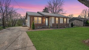 A single-story brick house with a front porch, a small front yard, and a driveway. - Cozy 3BR dog-friendly home just 13 min from Fort Campbell. Sleeps 6 with fast WiFi, a full kitchen, smart TVs and convenient access to APSU/F&M Bank Arena. (Clarksville)