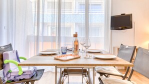 A dining area with a table set for two, a bottle, wine glasses, and a laptop on a chair. - Studio direct access to the beach with sea view, Wi-Fi and air conditioning (Palavas-les-Flots)