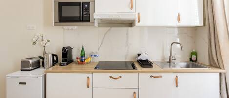 A compact kitchenette with a microwave, toaster, coffee maker, and a small refrigerator.