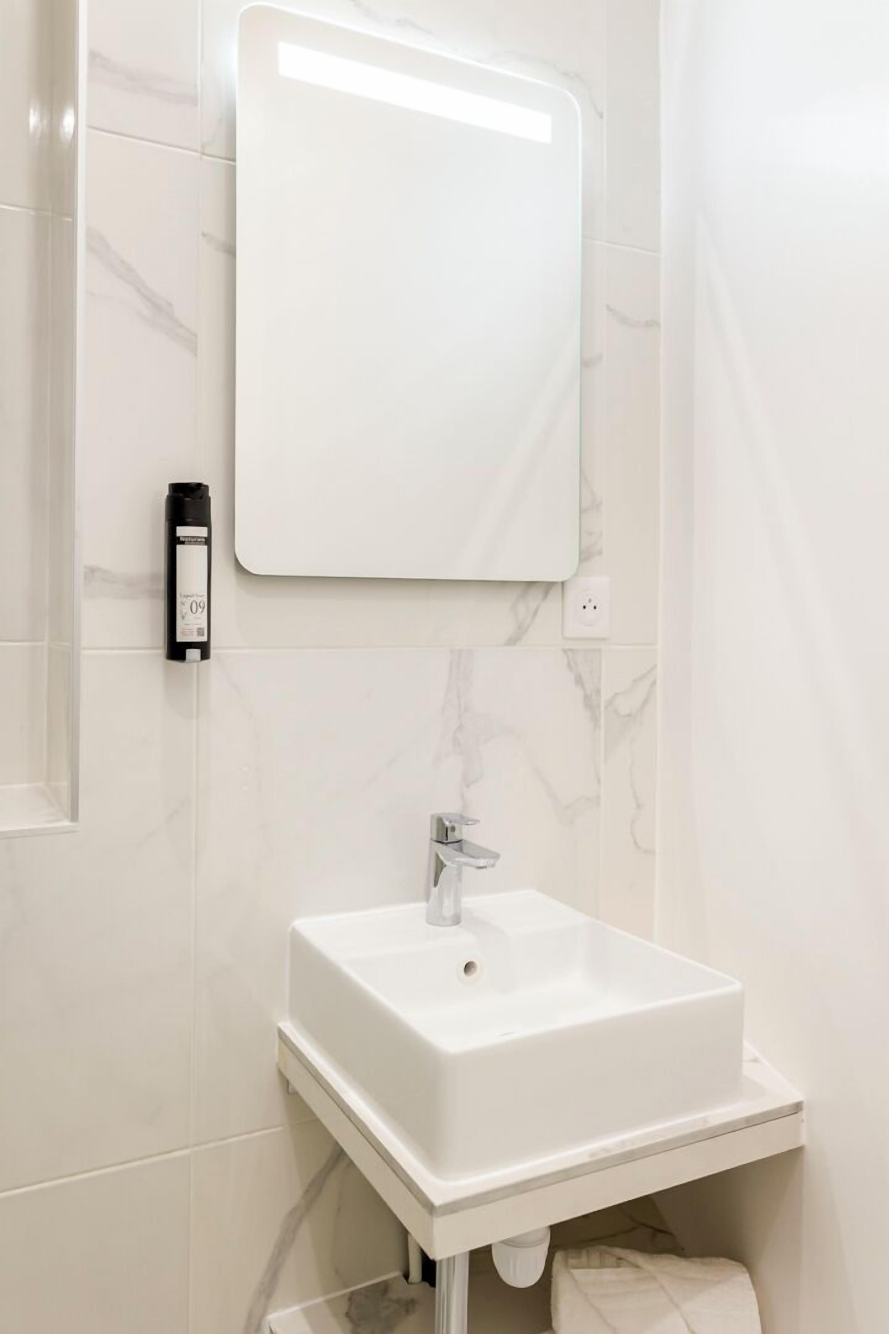 A modern bathroom with a white sink, a mirror, and a towel rack.