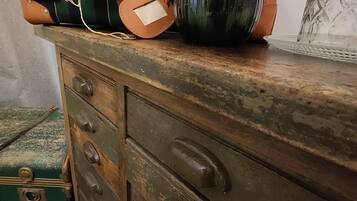 Eine antike Holzkommode mit mehreren Schubladen und einem grünen Koffer.