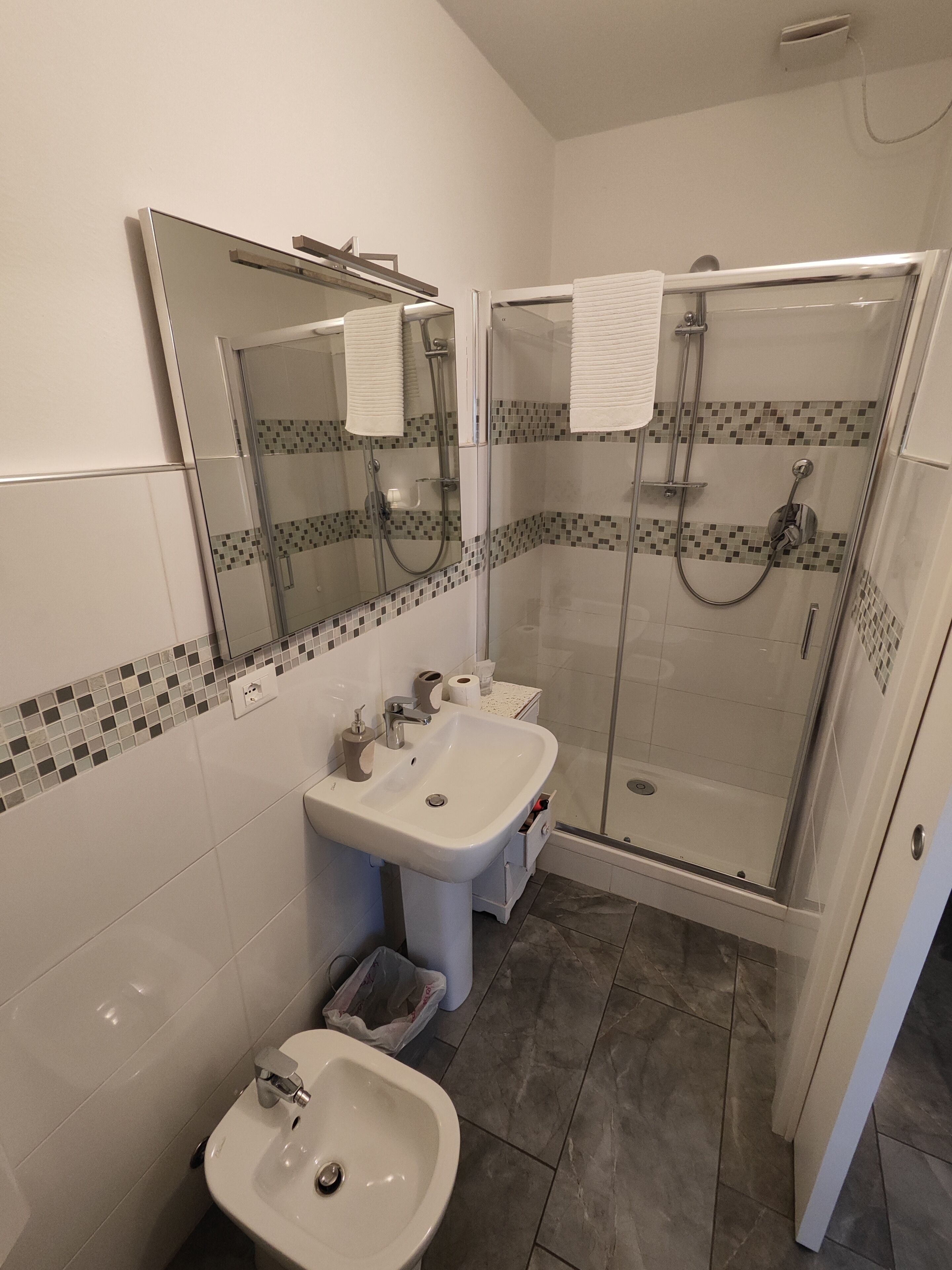 A modern bathroom with two sinks, a glass-enclosed shower, and a mirror with a tiled backsplash.